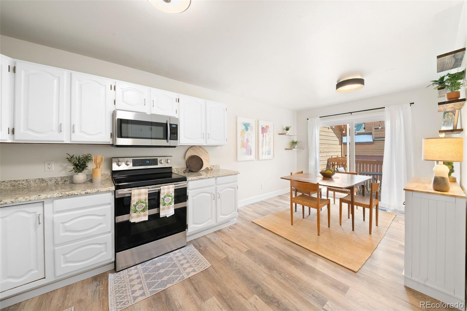 Kitchen and dining area with white cabinets, granite counters, and sliding doors to a deck.