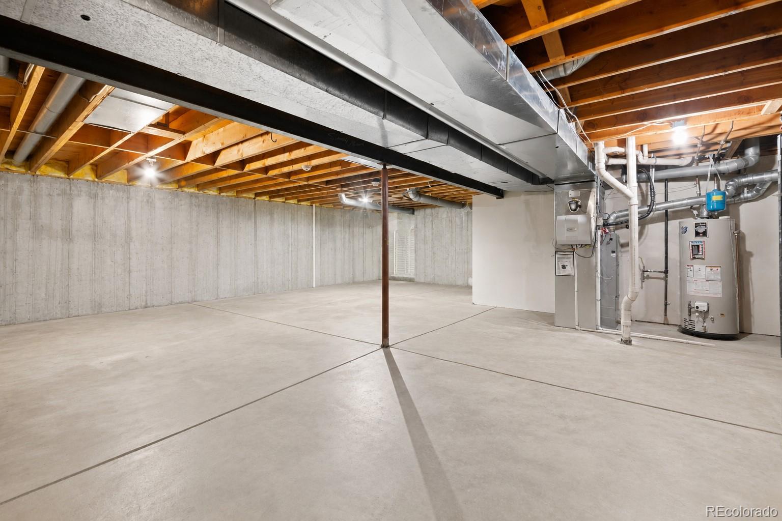 Unfinished basement with concrete floors, exposed ceiling joists, and utility equipment.