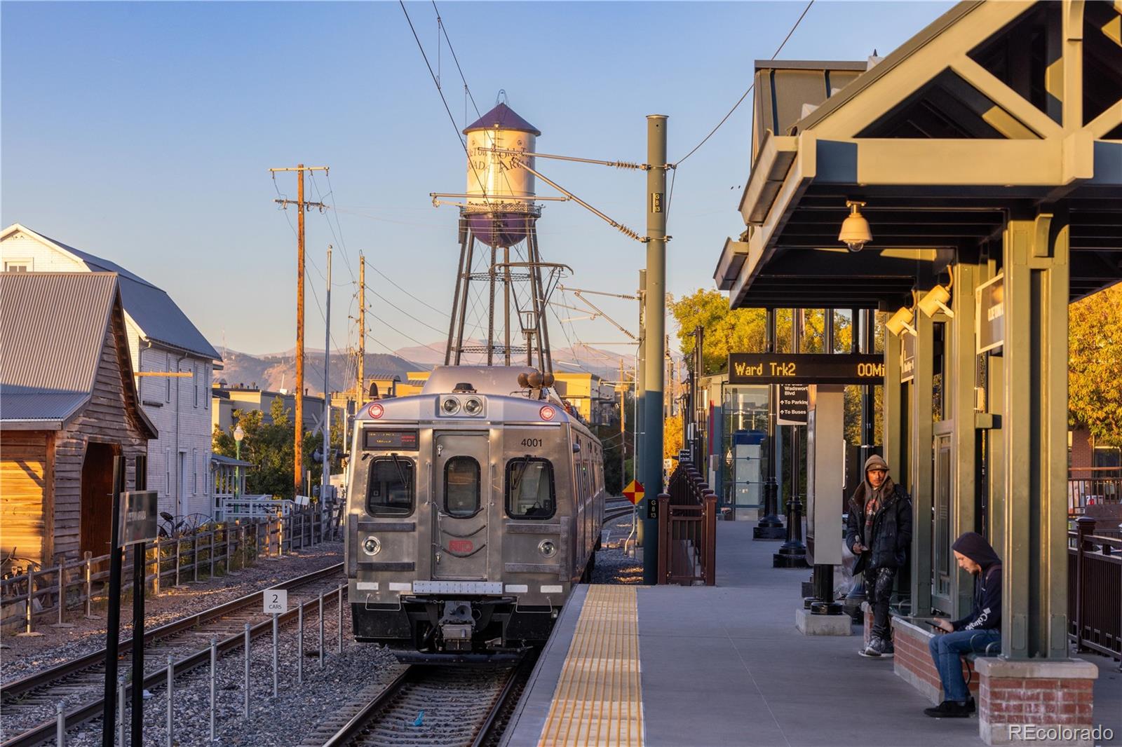 Commuter train at a covered station platform with a water tower behind it.