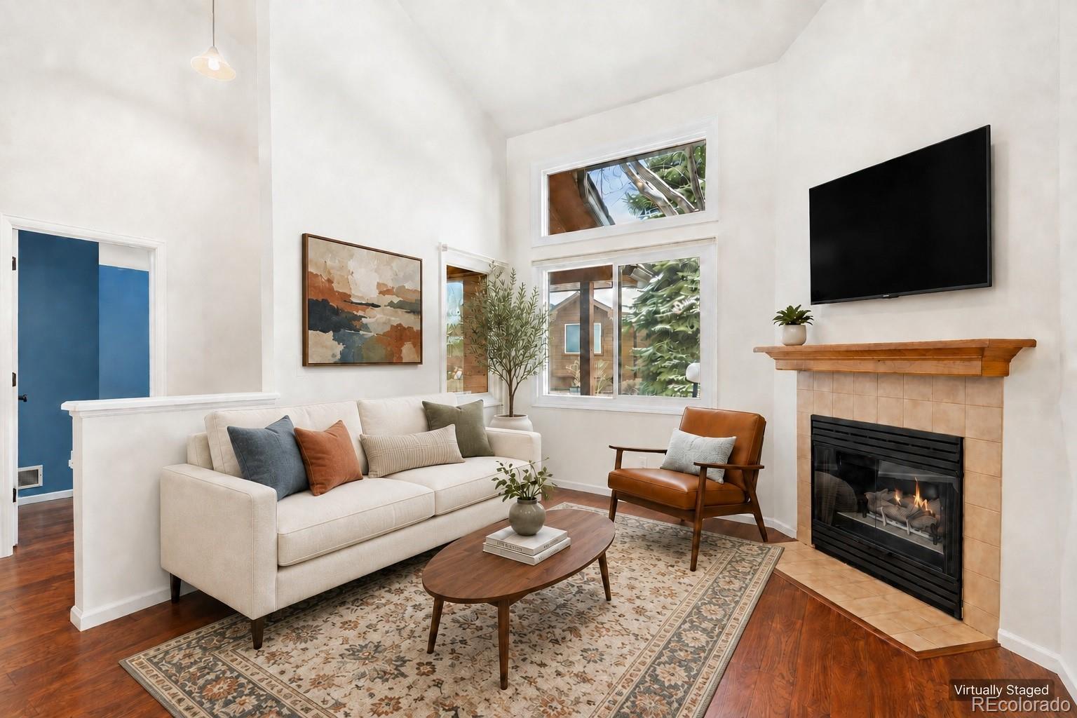 Virtually staged living room with a vaulted ceiling, tall windows, and a fireplace.