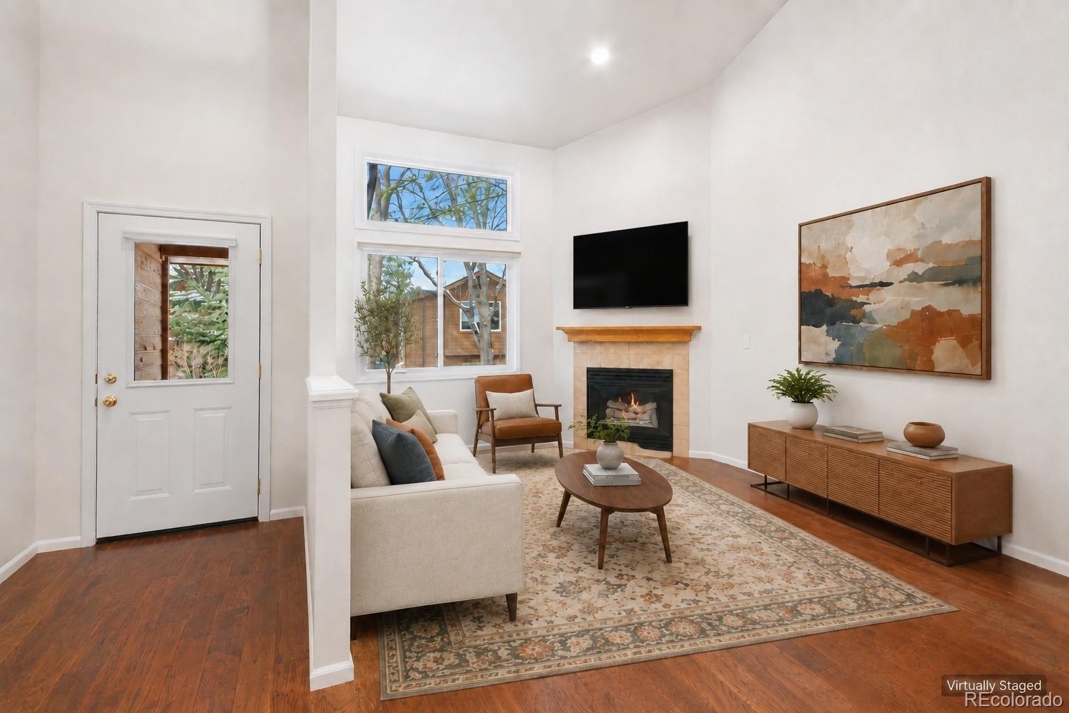 Virtually staged living room with a fireplace, large windows, hardwood floors, and contemporary furnishings.