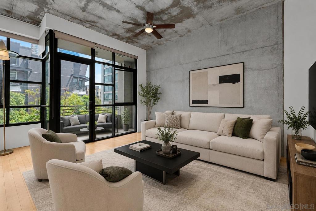 Furnished living room with concrete walls, a cream sofa, and large black-framed windows.