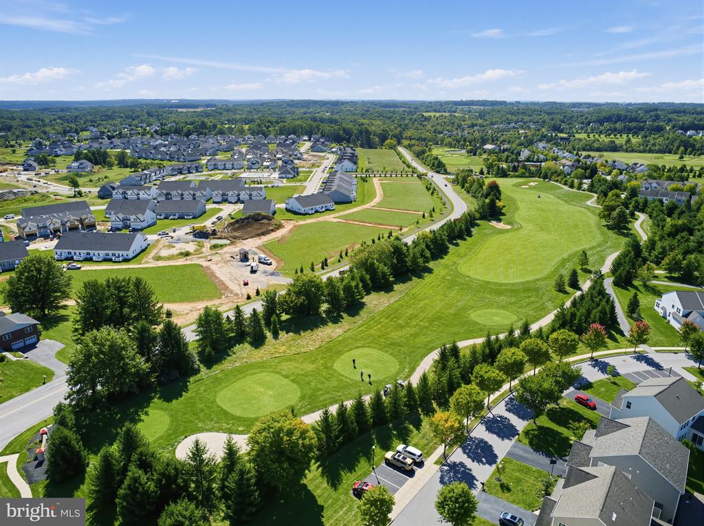 Aerial view of a golf course beside a residential development with homes under construction.