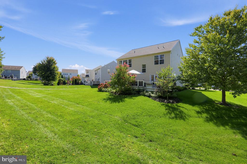 Rear of a two-story home overlooking a broad green lawn and landscaped yard.