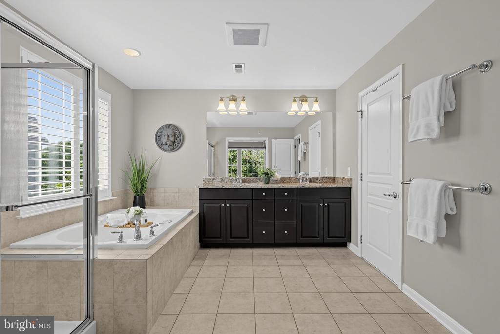 Spacious bathroom with a soaking tub, glass shower, and dark double vanity.