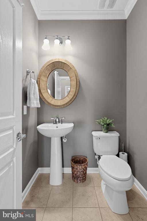Bathroom with a pedestal sink, oval wood-framed mirror, and gray walls.