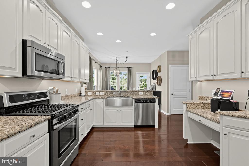 Kitchen with white cabinets, granite counters, stainless steel appliances, and dark wood floors.
