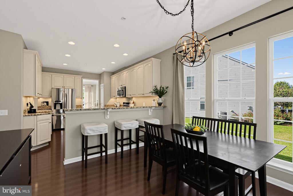 Kitchen and dining area with a granite breakfast bar, cream cabinets, and large windows.