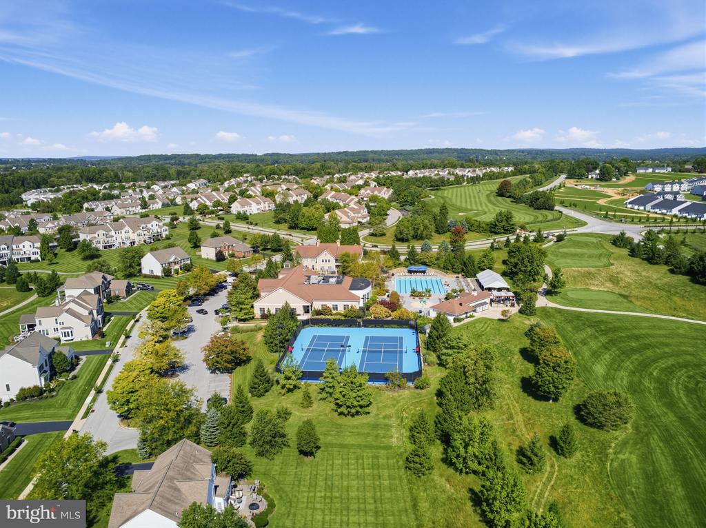 Aerial view of homes and community amenities, including tennis courts, a pool, and a golf course.