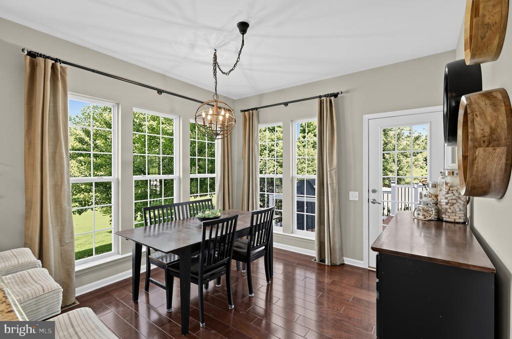 Dining room with a dark wood table, globe chandelier, and tall windows overlooking greenery.