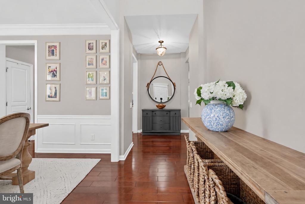 Entry foyer with hardwood floors, a gallery wall, and a console table topped with flowers.