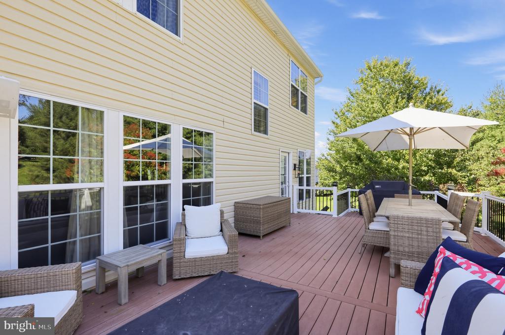 Furnished deck with wicker seating and a dining table beneath a white umbrella.