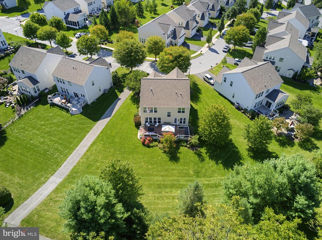 Aerial view of a home with a rear deck and patio opening onto a broad lawn.