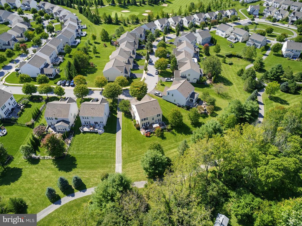Aerial view of detached homes and lawns beside a broad green open space.