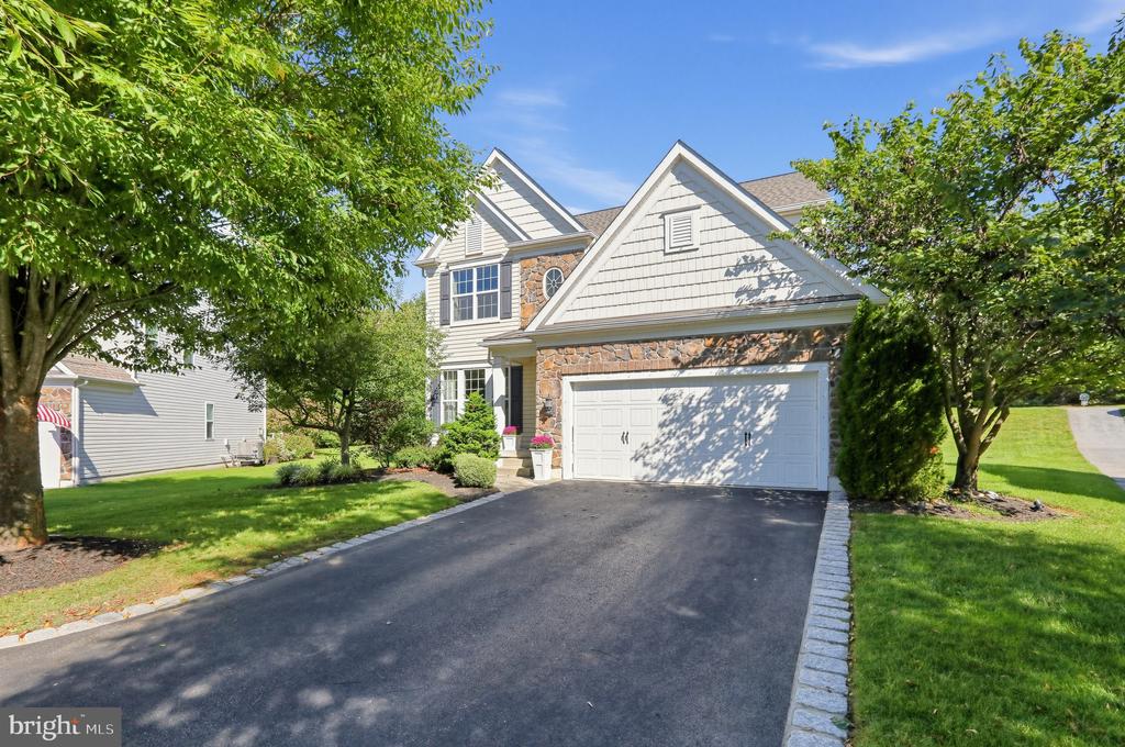 Two-story home with stone accents, a white double garage door, and a wide paved driveway.