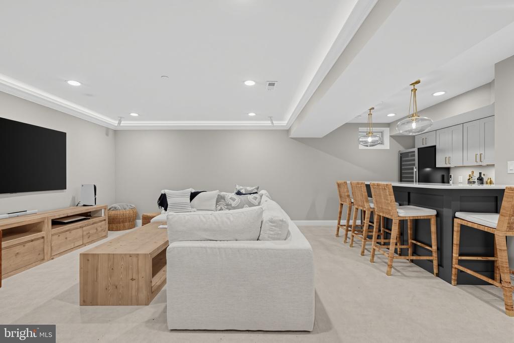 Furnished living room with a light sectional and wood coffee table beside a modern kitchen island.
