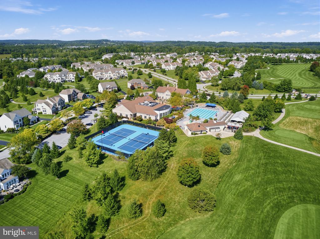 Aerial view of a residential community with a pool, tennis courts, and golf course.
