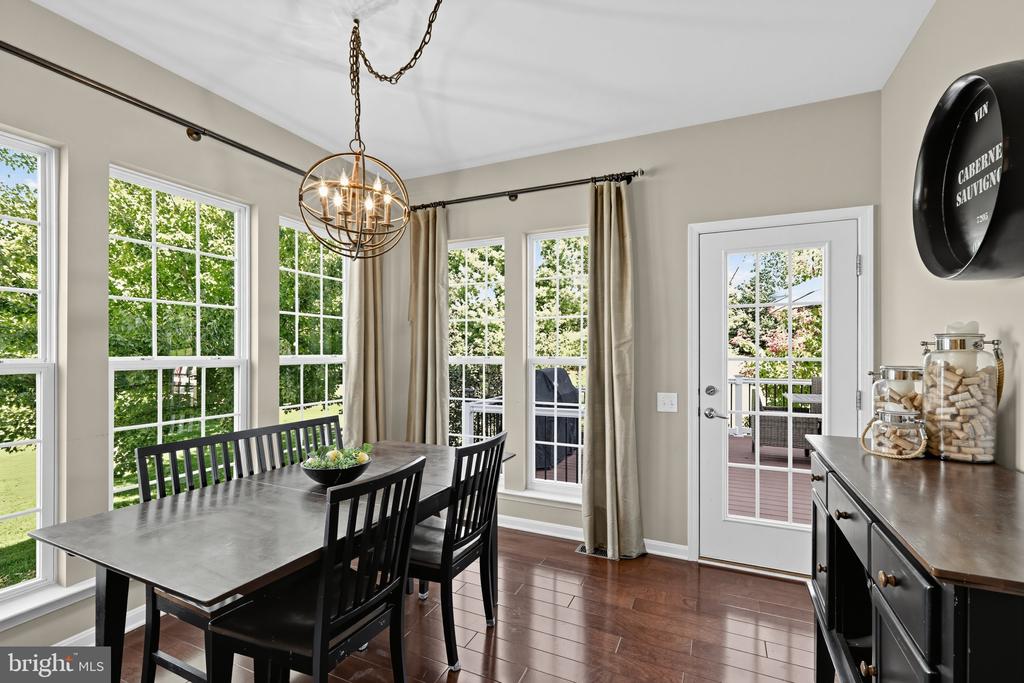 Dining area with a dark table, black chairs, bronze chandelier, and windows beside a glass-paned deck door.