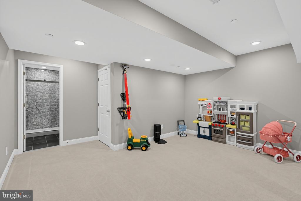 Finished playroom with a toy kitchen, ride-on car, and pink stroller.