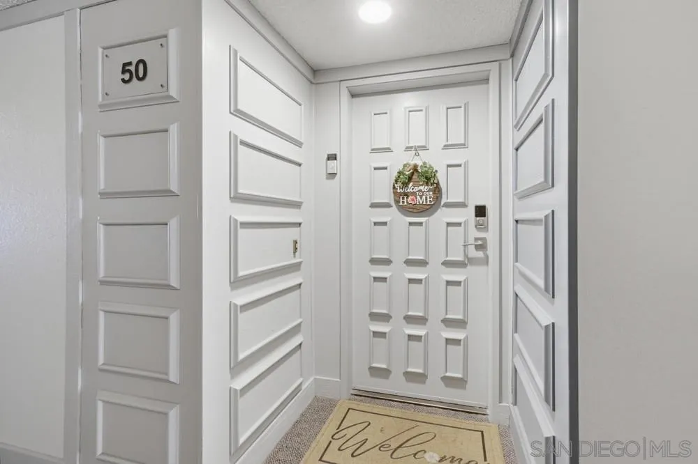 Condo entryway with white paneled walls, unit number 50, and a welcome mat.