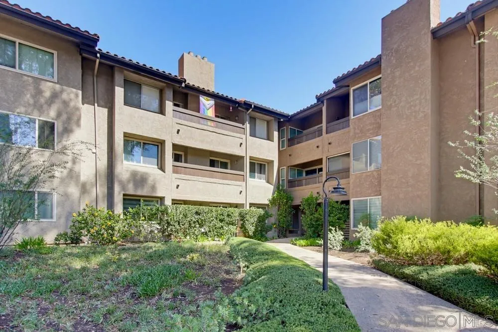 Condominium courtyard with landscaped paths and multi-story stucco buildings.
