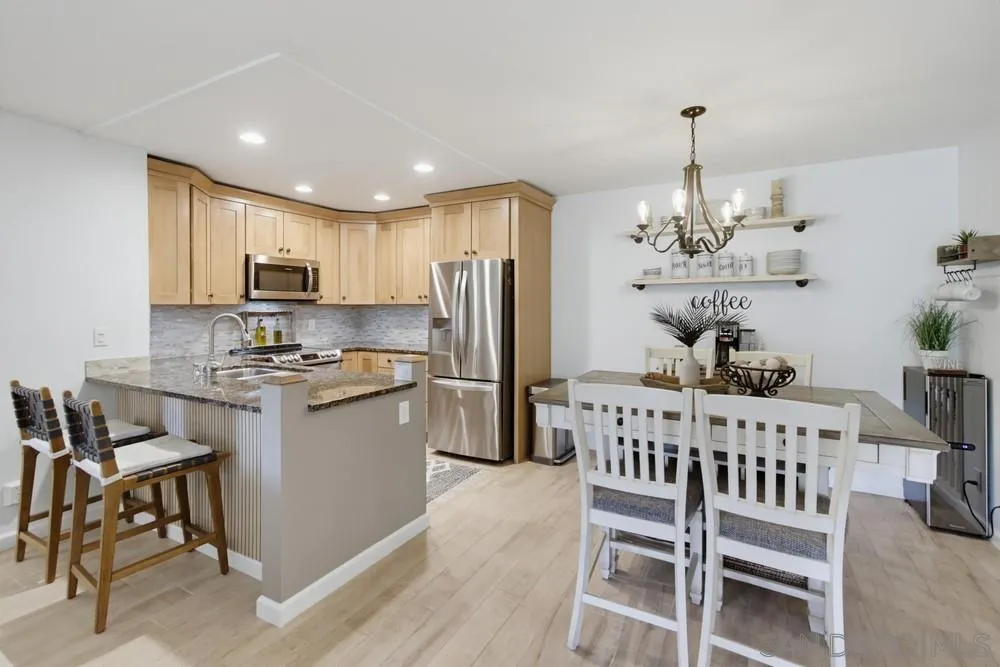 Kitchen with a stone-topped island, stainless steel appliances, and an adjoining dining area.