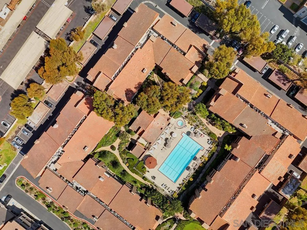 Aerial view of terracotta-roofed condominiums surrounding a landscaped courtyard and swimming pool.