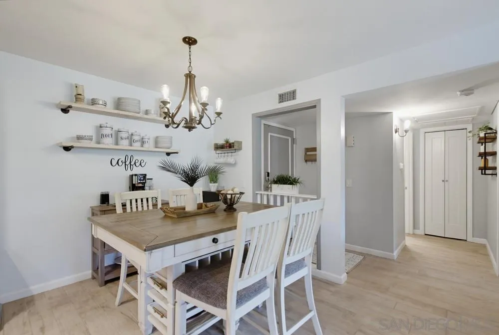 Dining room with a white farmhouse table, open dishware shelves, and a brass chandelier.