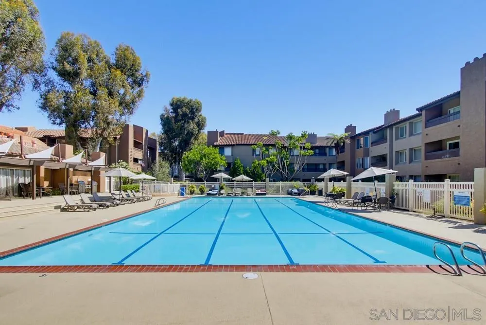 Outdoor pool with lane markings and lounge chairs, surrounded by apartment buildings.