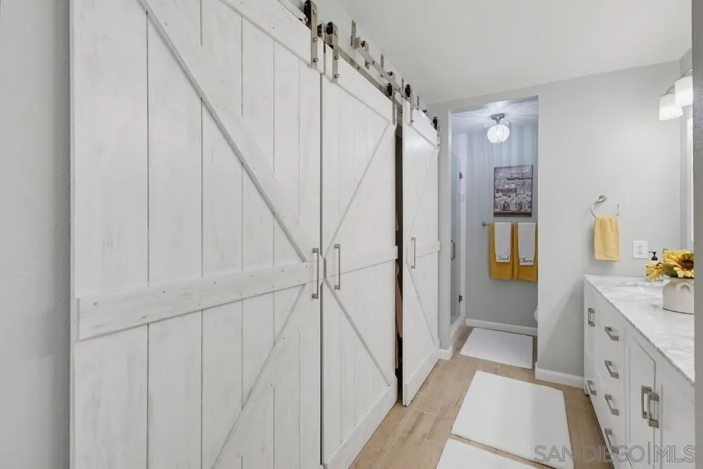 Bathroom with white sliding barn doors, a long vanity, and yellow towels.