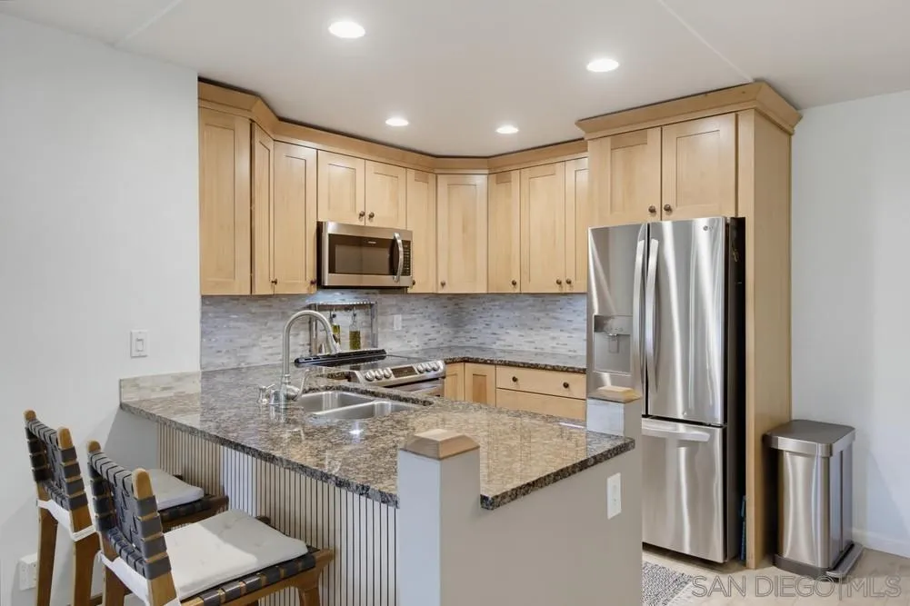 Kitchen with light wood cabinets, granite counters, and stainless steel appliances.