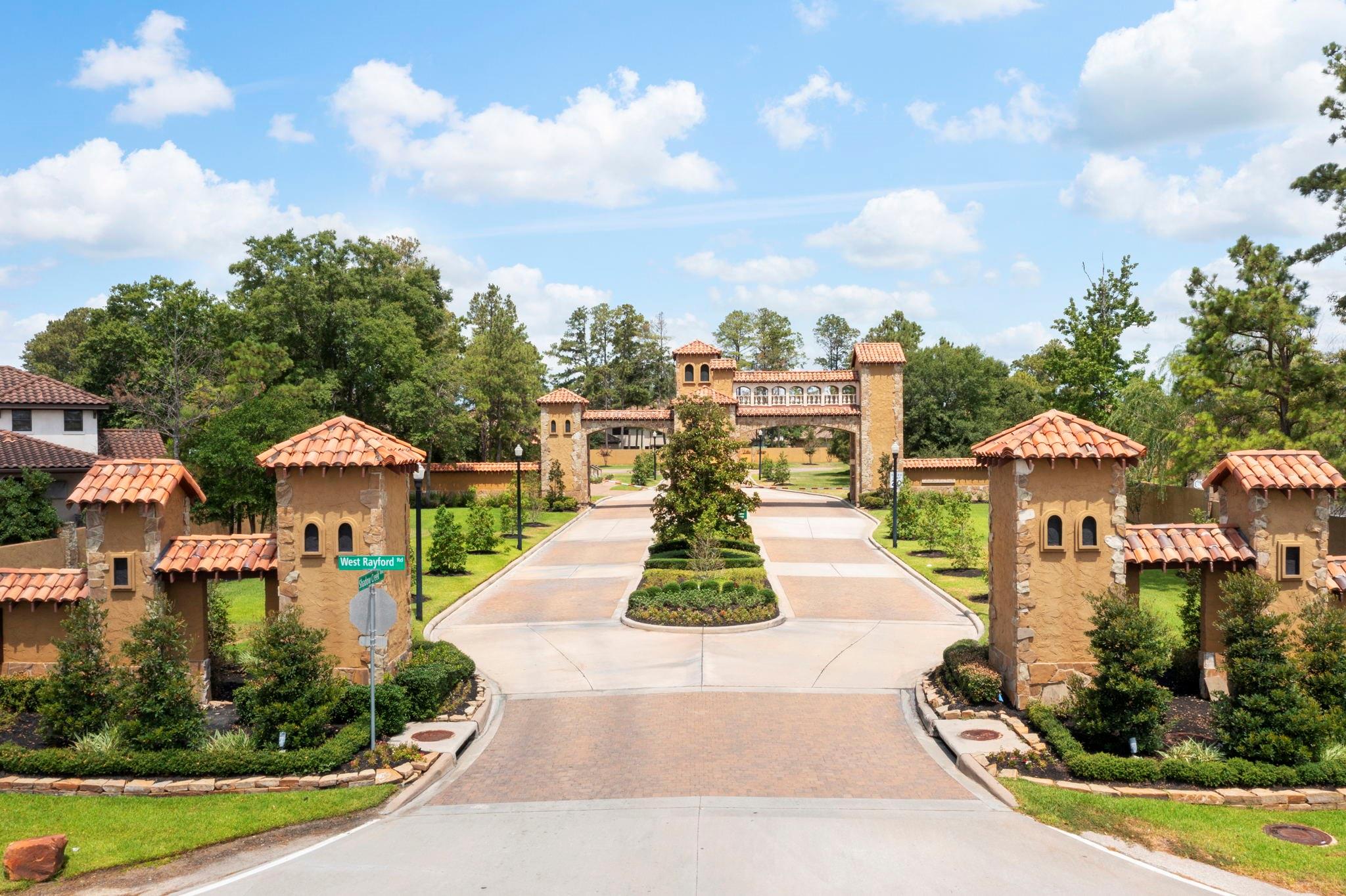 Residential entrance with a Spanish-style stone gateway and terracotta-roofed gate structures.