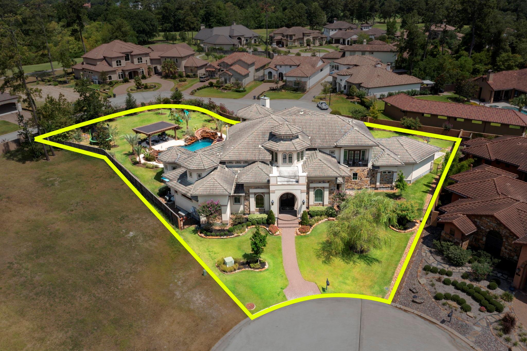 Aerial view of a large home and landscaped lot outlined in yellow, with a backyard pool and covered patio.