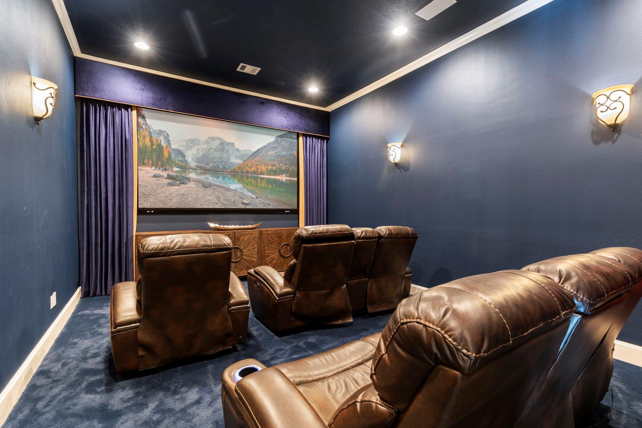 Home theater with brown leather recliners, blue walls, and a large projection screen.