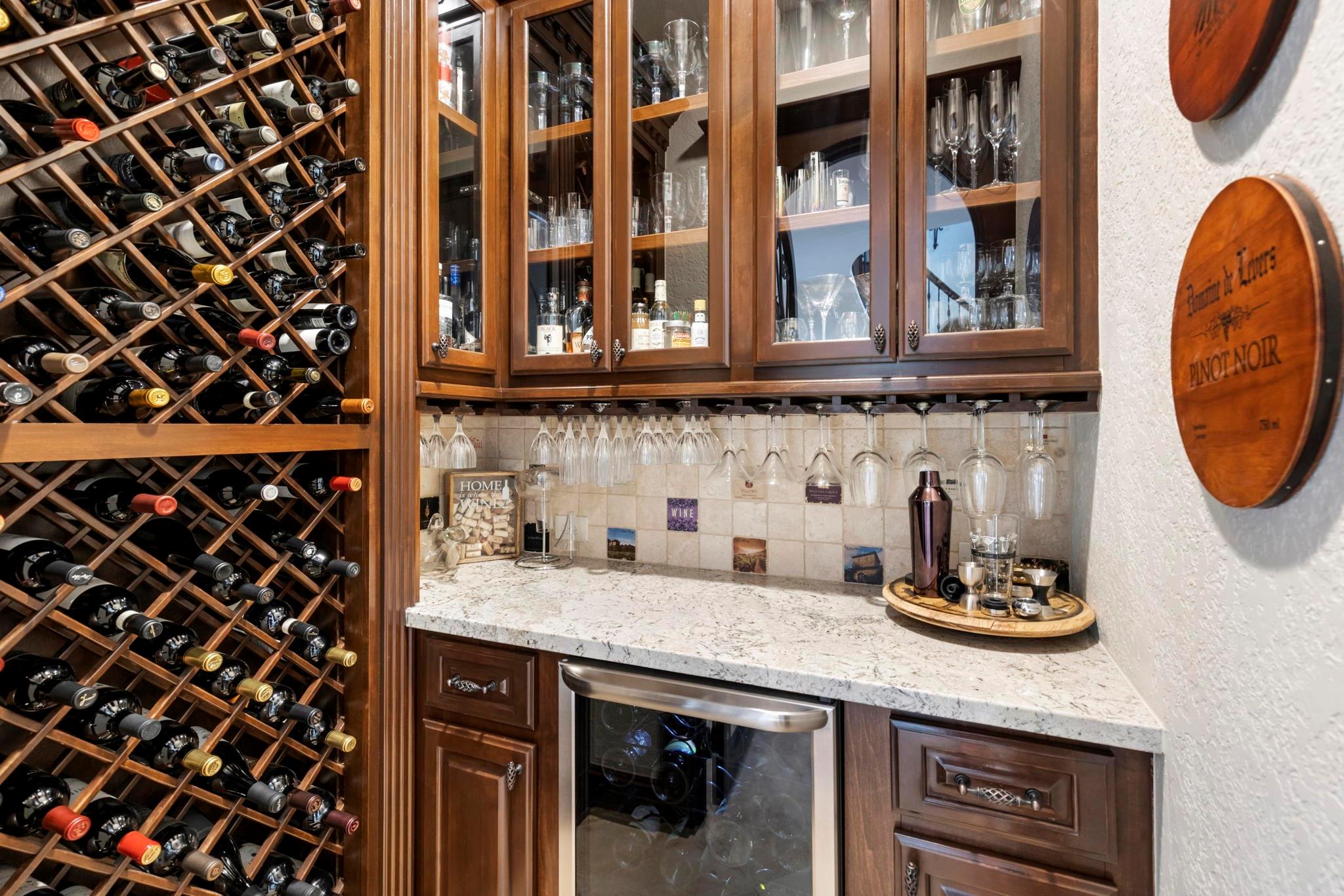Wine cellar with a large wooden bottle rack, glass-front cabinets, and a stone counter.