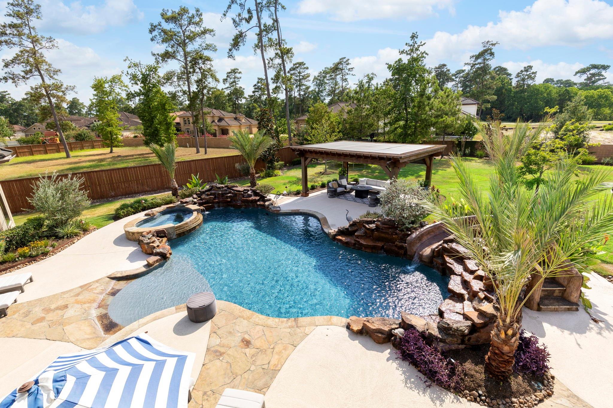 Backyard pool and spa with a rock waterfall and covered patio.