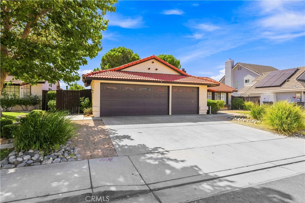Single-story home with a red tile roof, two-car garage, and broad concrete driveway.
