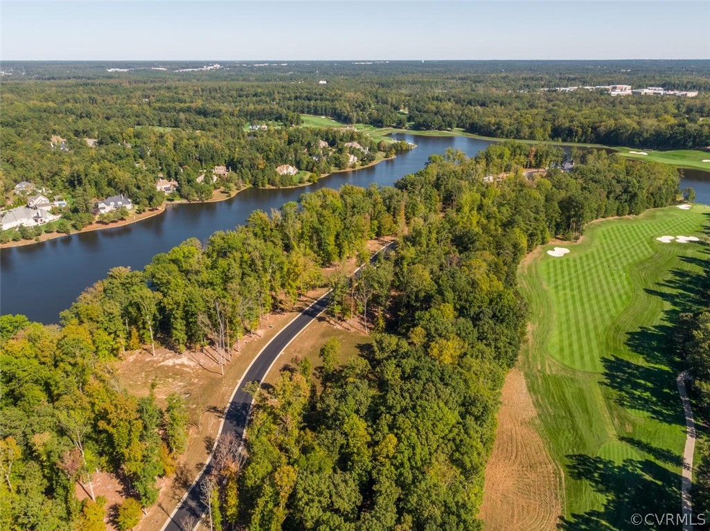 Aerial view of wooded homes beside a winding lake and manicured golf course.