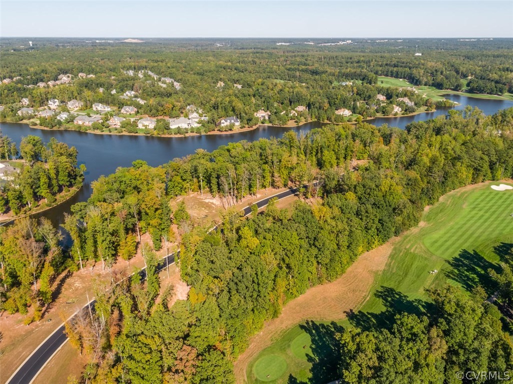 Aerial view of a wooded shoreline beside a winding river and golf course.
