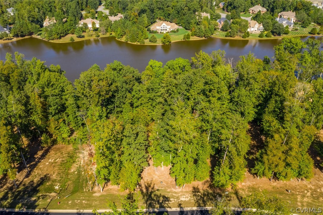 Aerial view of a wooded riverfront property, with homes across the water.