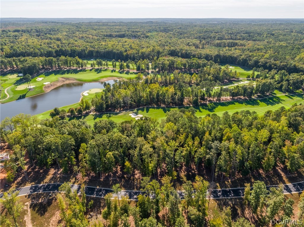 Aerial view of a golf course winding through woods, with a pond and sand bunkers.