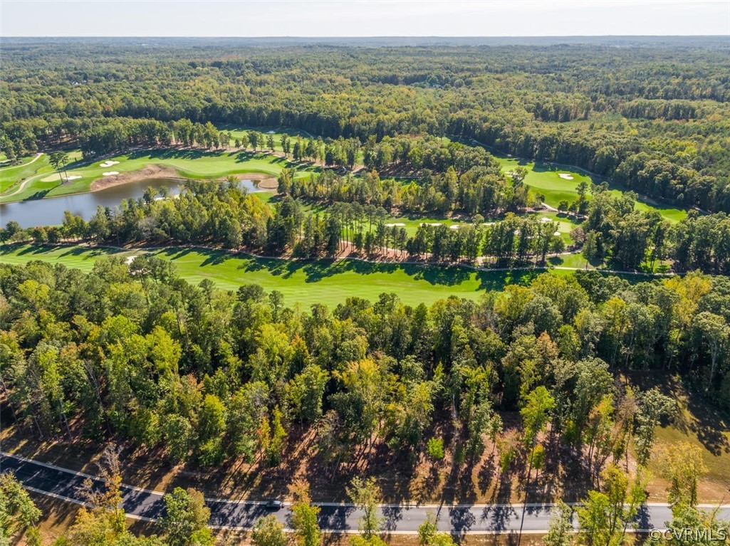 Aerial view of wooded golf course with a pond, fairways, and sand bunkers.
