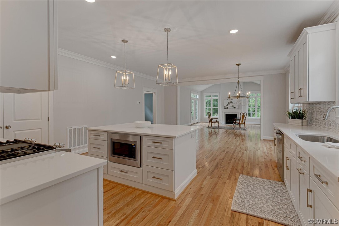 Open-plan kitchen with a large white island, hardwood floors, and a fireplace in the adjoining sitting area.