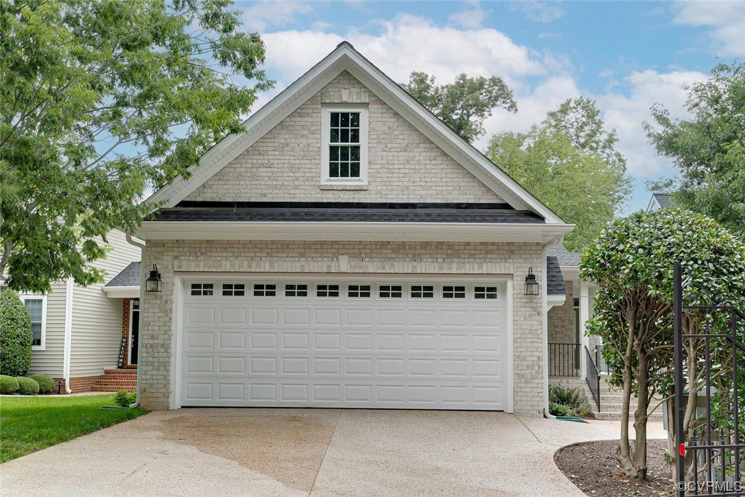 Light brick home with a front-facing gable, wide double garage, and concrete driveway.