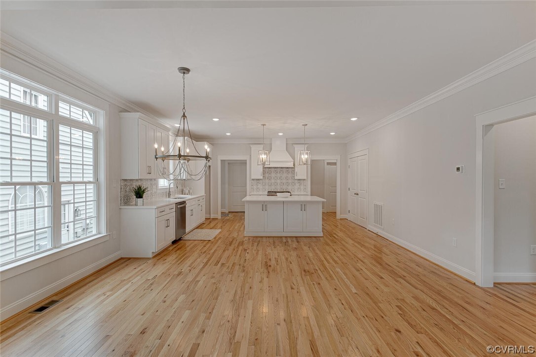 Open-plan kitchen with a large island, white cabinetry, hardwood floors, and tall shuttered windows.