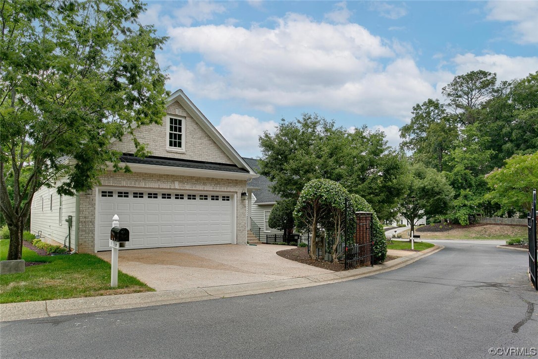 Home exterior with a double garage and wide driveway beneath mature trees.