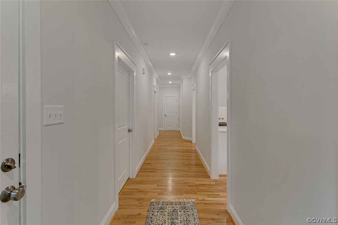 Hallway with hardwood floors, white doors, recessed lights, and a patterned runner.