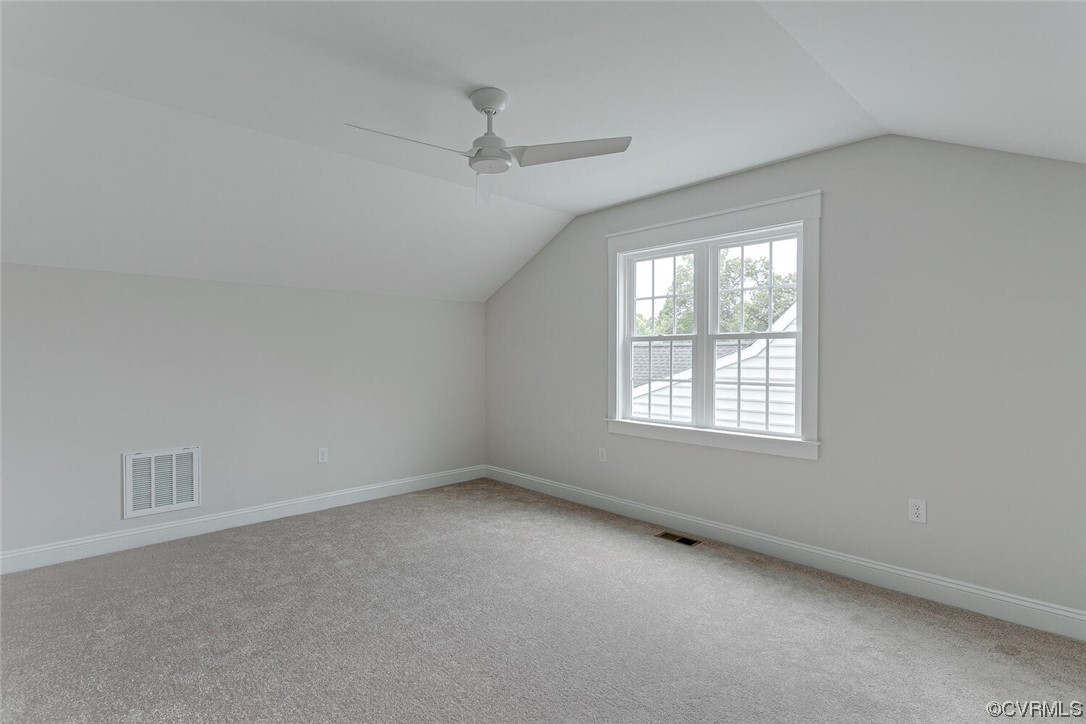 Empty carpeted bedroom with a ceiling fan and large window.