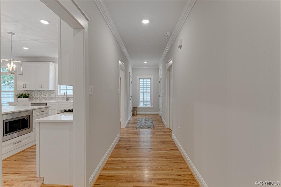 Hallway with hardwood floors and a view into a white kitchen.