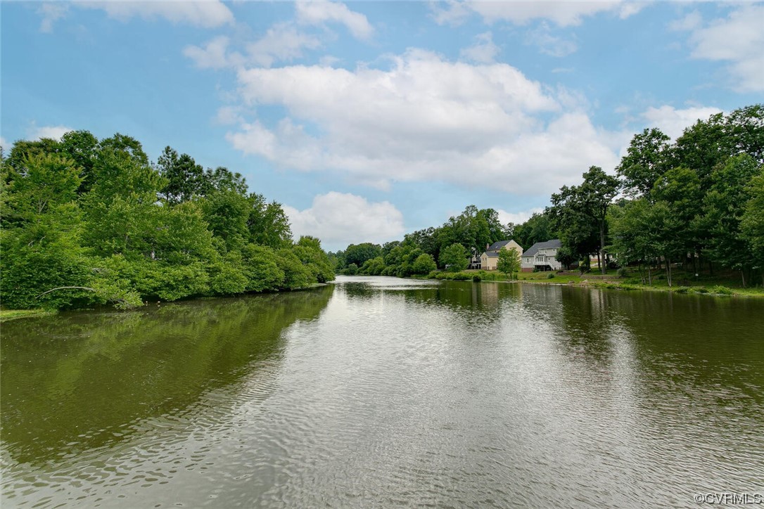 Lake bordered by trees, with several homes along the far shore.